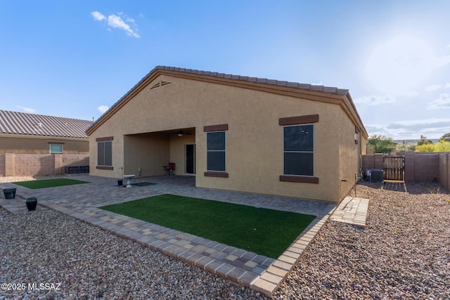 rear view of house with a fenced backyard, central AC unit, a patio area, a ceiling fan, and stucco siding