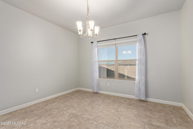 spare room featuring a chandelier and baseboards