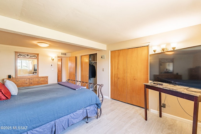bedroom with baseboards, visible vents, and two closets