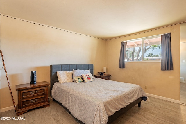 bedroom with baseboards and wood finished floors