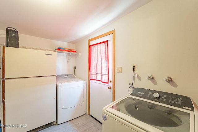 laundry area with washing machine and clothes dryer, laundry area, and light wood-style flooring