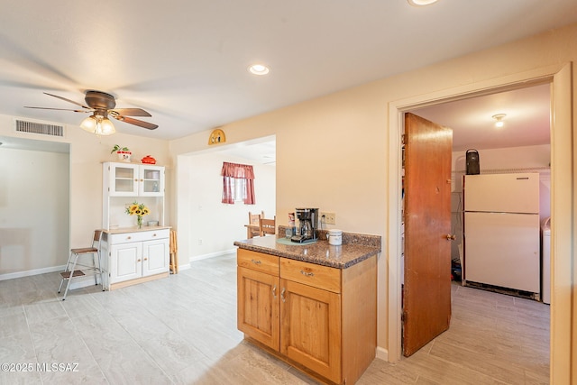 kitchen featuring visible vents, freestanding refrigerator, light wood-type flooring, baseboards, and ceiling fan