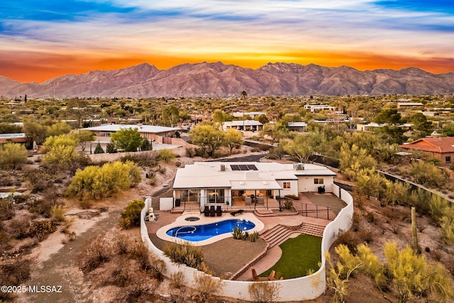 3855 N Via Avellana, Tucson, AZ 85718 - back of house at dusk with a jacuzzi, a mountain view, an outdoor pool, and a patio area