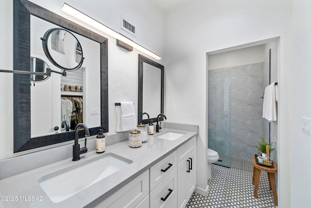 3855 N Via Avellana, Tucson, AZ 85718 - bathroom with double vanity, toilet, a spacious closet, a tile shower, and tile patterned flooring