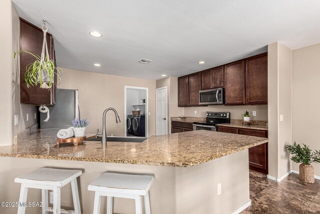 9528 S Desert Fauna Loop, Tucson, AZ 85747 - kitchen with visible vents, a sink, washing machine and clothes dryer, a peninsula, and appliances with stainless steel finishes