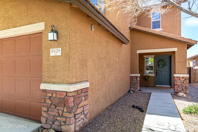 9528 S Desert Fauna Loop, Tucson, AZ 85747 - doorway to property featuring a garage, stone siding, and stucco siding