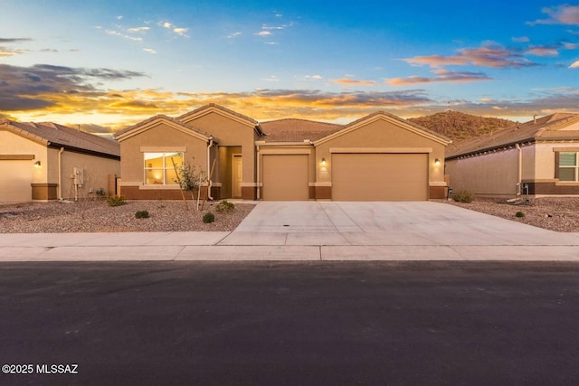 single story home with an attached garage, a tile roof, concrete driveway, and stucco siding