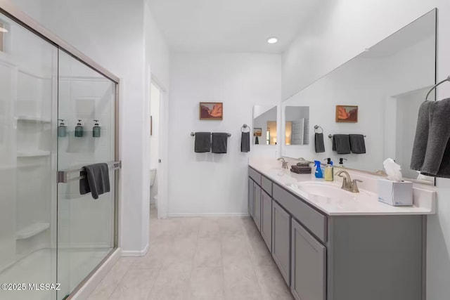 bathroom with double vanity, baseboards, a stall shower, and a sink