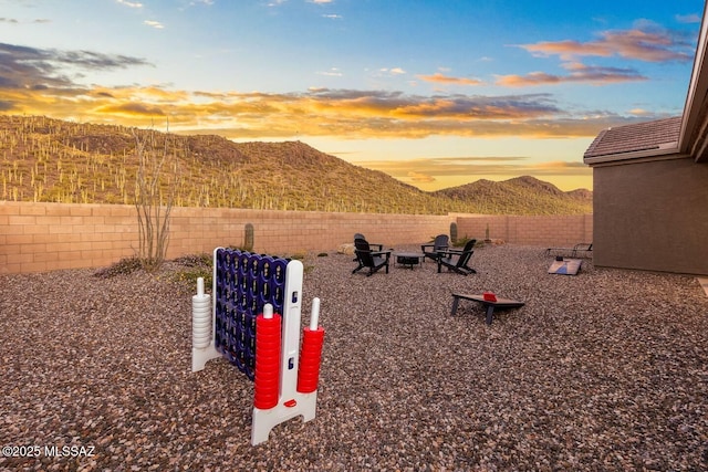 view of yard with a fire pit, a fenced backyard, and a mountain view