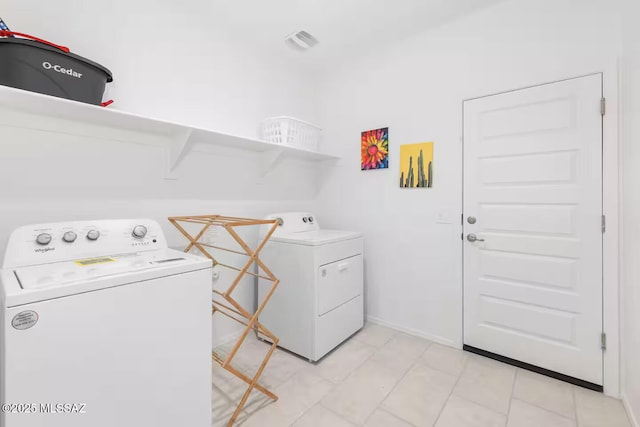 laundry room with washing machine and dryer, visible vents, light tile patterned floors, and laundry area