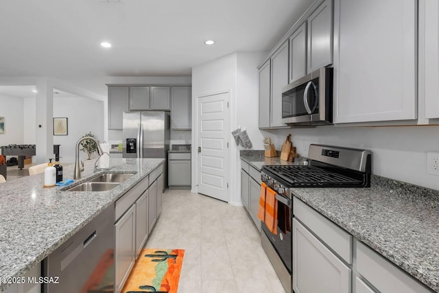 kitchen with stainless steel appliances, a sink, recessed lighting, gray cabinetry, and light stone counters