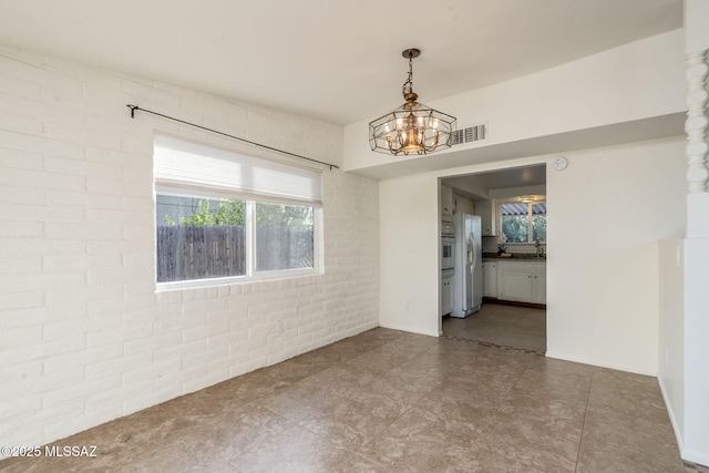 2826 W Jacinto St, Tucson, AZ 85745 - unfurnished room with brick wall, a chandelier, a sink, and dark tile patterned flooring