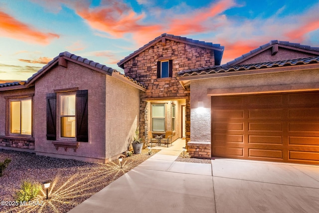 5596 W Lazy Farm Dr, Tucson, AZ 85742 - view of front of home featuring a tile roof, concrete driveway, stone siding, a garage, and stucco siding