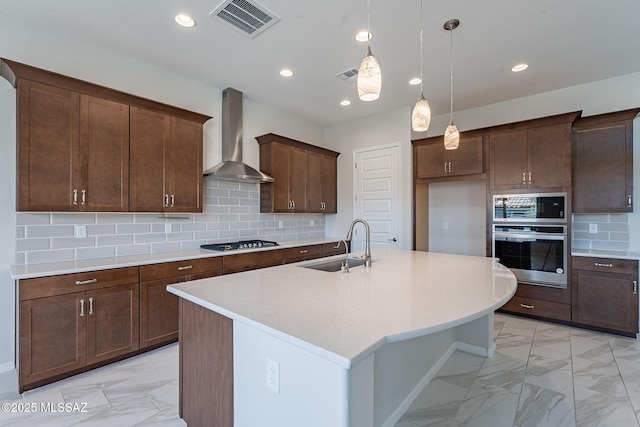 435 E Day Flower Dr, Tucson, AZ 85755 - kitchen featuring stainless steel appliances, wall chimney range hood, light marble finish floors, a kitchen island with sink, and decorative light fixtures