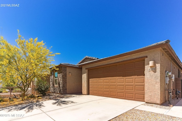 view of front facade featuring an attached garage, driveway, stone siding, and stucco siding