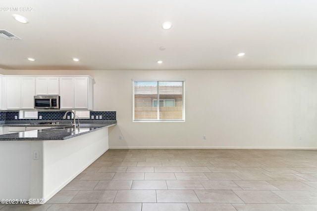 kitchen with white cabinets, stainless steel microwave, visible vents, recessed lighting, and decorative backsplash