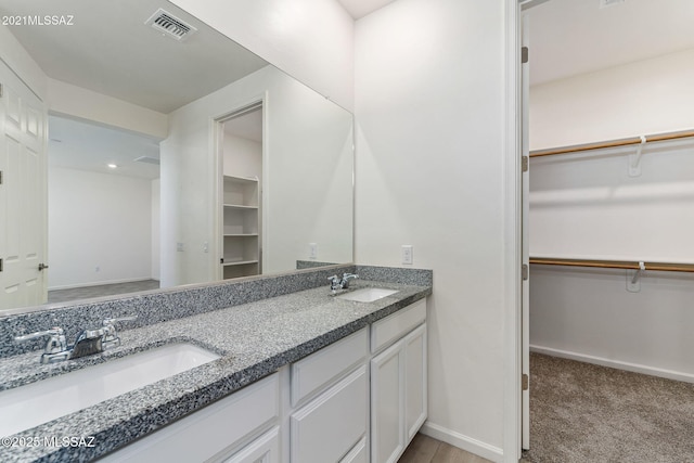 full bath with baseboards, a sink, visible vents, and double vanity