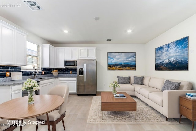 living room featuring light wood-type flooring, visible vents, and recessed lighting