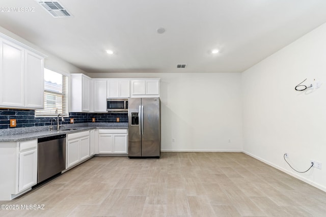 kitchen with backsplash, visible vents, appliances with stainless steel finishes, and a sink