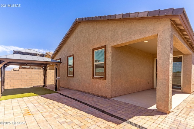 exterior space with a gazebo, a patio, stucco siding, and fence