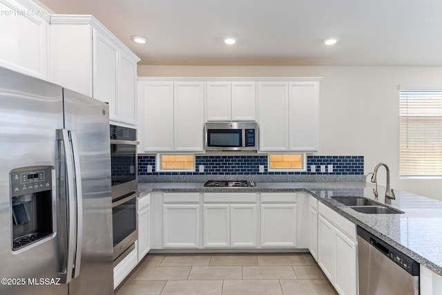 kitchen featuring white cabinets, backsplash, stainless steel appliances, and a sink