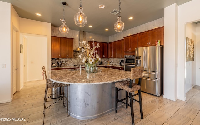 13274 Humphreys Peak Dr, Oro Valley, AZ 85755 - kitchen featuring wall chimney range hood, a breakfast bar area, tasteful backsplash, appliances with stainless steel finishes, and visible vents