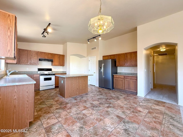 2582 W Brandy Crest Dr, Tucson, AZ 85713 - kitchen with white range with gas stovetop, stainless steel fridge with ice dispenser, arched walkways, rail lighting, and under cabinet range hood