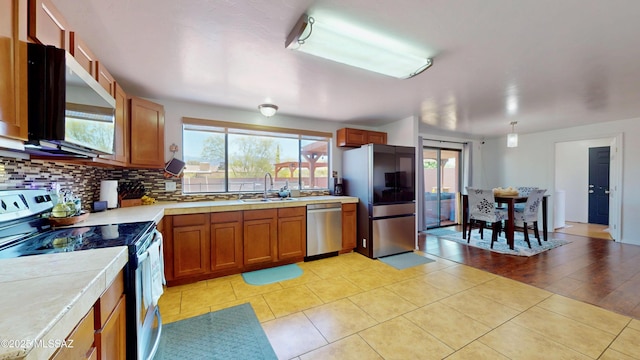 502 N Citadel Ave, Tucson, AZ 85748 - kitchen with a sink, brown cabinetry, decorative backsplash, light tile patterned flooring, and stainless steel appliances