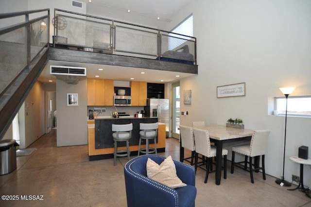 dining space with a high ceiling, visible vents, and plenty of natural light