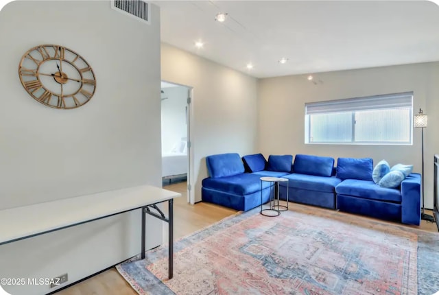 living room with visible vents, recessed lighting, and wood finished floors