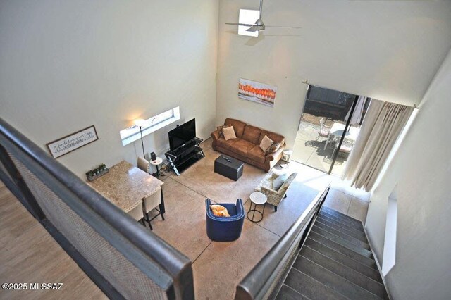 living area featuring a towering ceiling, ceiling fan, and wood finished floors