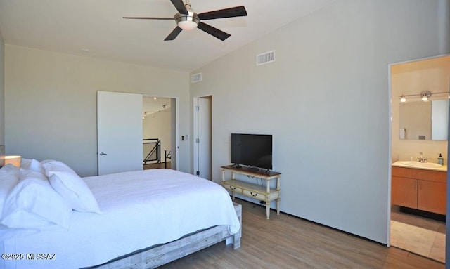 bedroom with visible vents, a sink, light wood-style flooring, and connected bathroom