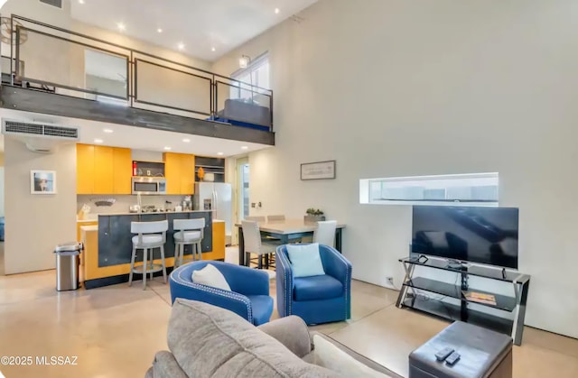 living room featuring a high ceiling, concrete flooring, and visible vents