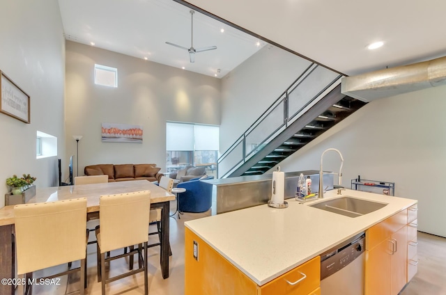 kitchen with ceiling fan, a sink, an island with sink, open floor plan, and stainless steel dishwasher