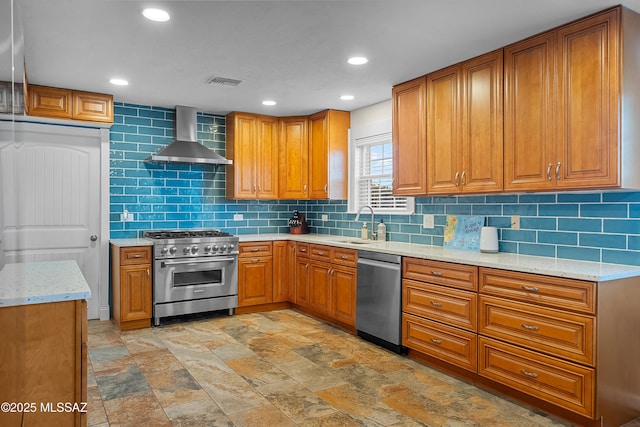 kitchen featuring wall chimney exhaust hood, visible vents, decorative backsplash, brown cabinetry, and appliances with stainless steel finishes
