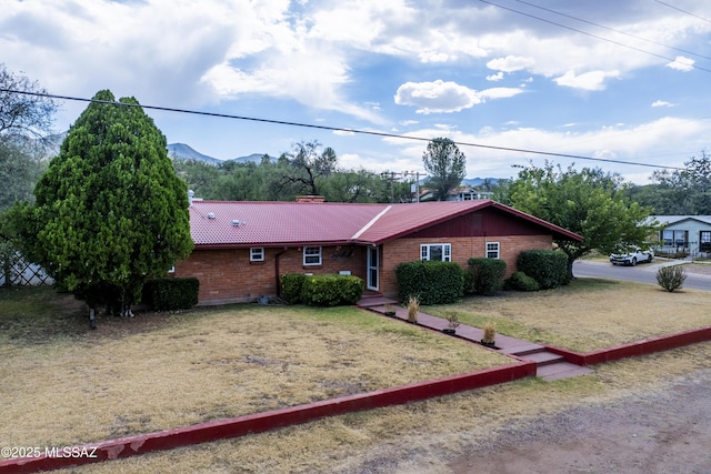 ranch-style home with a chimney, a tile roof, and a mountain view