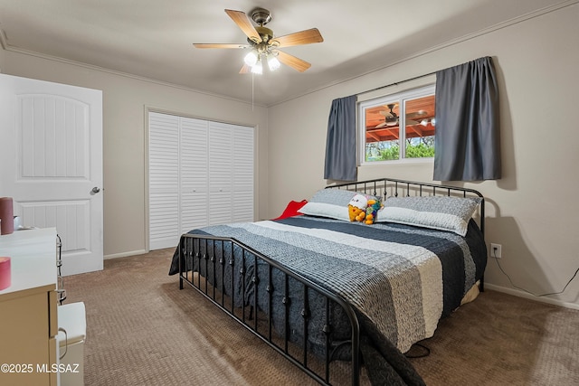 carpeted bedroom with ornamental molding, baseboards, a ceiling fan, and a closet