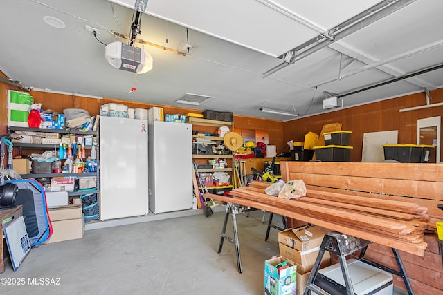 garage with wood walls, freestanding refrigerator, and a garage door opener