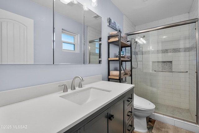 bathroom featuring toilet, vanity, visible vents, and a stall shower