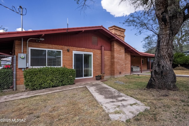 rear view of property featuring a chimney and a yard