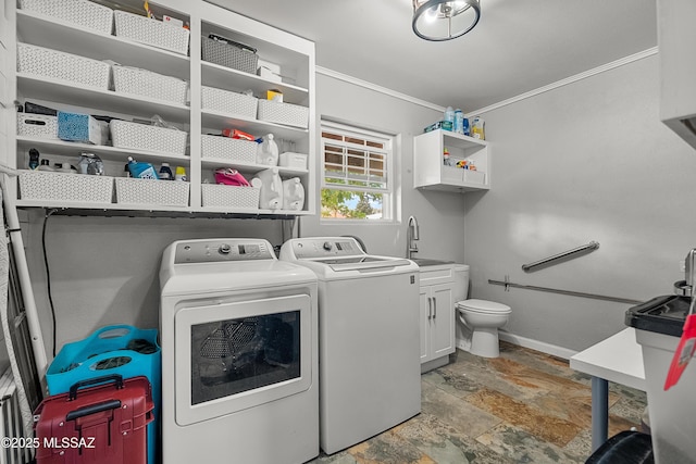 clothes washing area featuring crown molding, stone tile floors, washer and dryer, baseboards, and laundry area