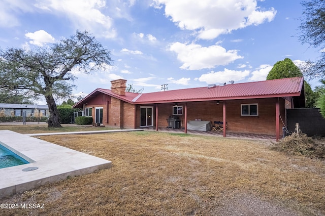 rear view of property featuring a chimney, a yard, an outdoor pool, and a patio area