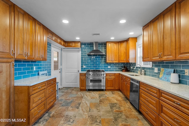 kitchen with wall chimney range hood, a sink, brown cabinets, appliances with stainless steel finishes, and visible vents