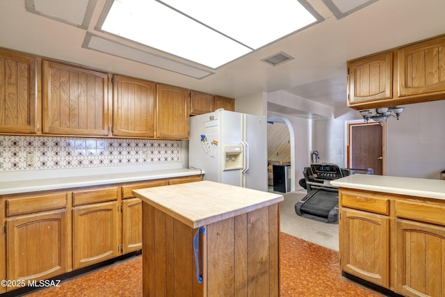 601 N Sahuara Ave, Tucson, AZ 85711 - kitchen with visible vents, a kitchen island, light countertops, arched walkways, and white fridge with ice dispenser