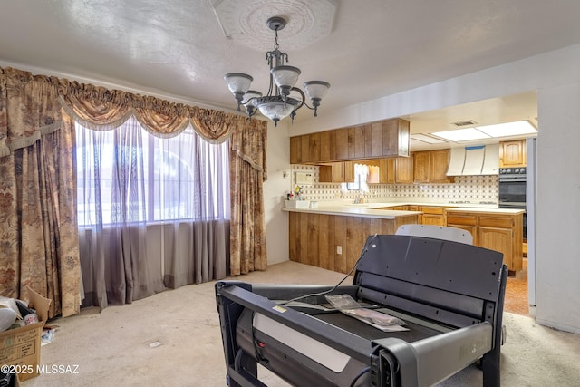 601 N Sahuara Ave, Tucson, AZ 85711 - kitchen featuring backsplash, light colored carpet, light countertops, an inviting chandelier, and black oven
