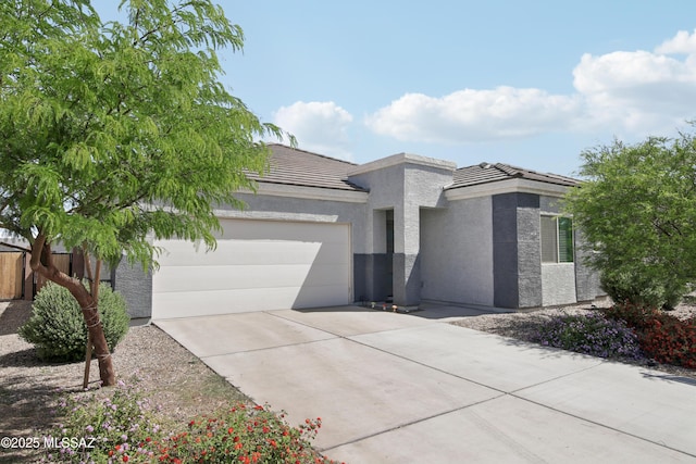 modern home featuring stucco siding, concrete driveway, an attached garage, and a tile roof