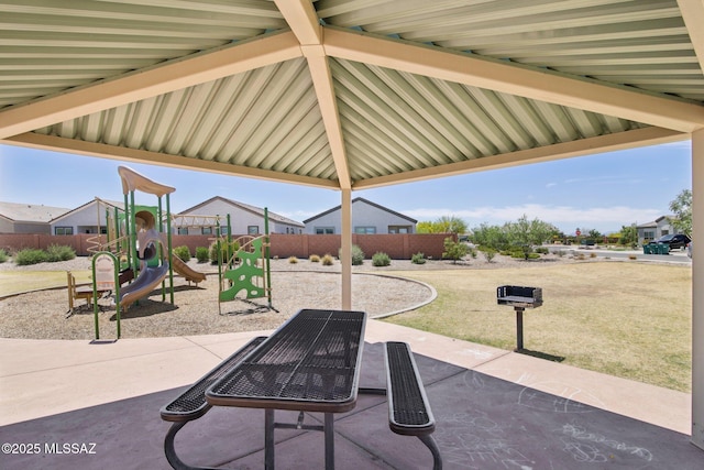 view of patio with playground community and fence