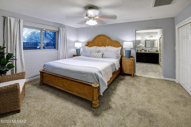 bedroom with baseboards, visible vents, light colored carpet, ceiling fan, and connected bathroom