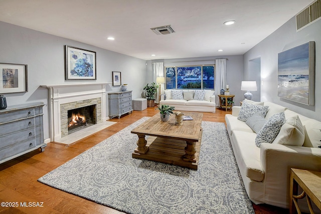 living room featuring a fireplace with flush hearth, wood finished floors, visible vents, and recessed lighting