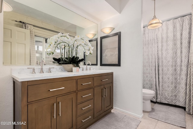 full bathroom featuring toilet, tile patterned floors, double vanity, and a sink